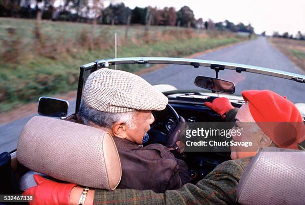 senior couple driving convertible in the country - sporthandschuh stock-fotos und bilder
