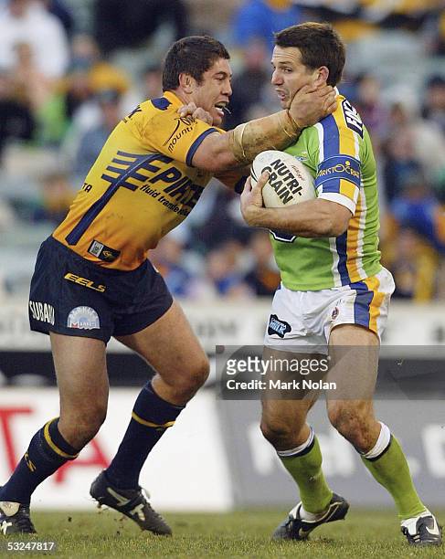 Clinton Schifcofske of the Raiders is tackled by Nathan Cayless of the Eels during the round 19 NRL match between the Canberra Raiders and the...