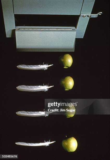 feather & apple drop in vacuum chamber - feather stockfoto's en -beelden