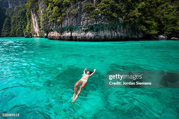 a woman floating on her back in tropical water. - phuket stock-fotos und bilder