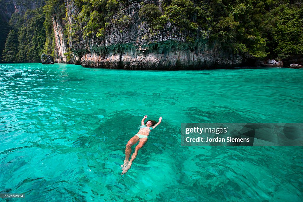 A woman floating on her back in tropical water.