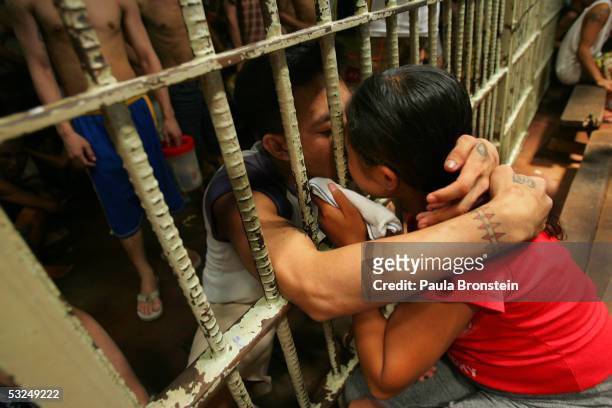 Couple kisses through the bars in a cell packed with several dozen inmates at the Navotas Municipal jail July 17, 2005 in Navotas, Manila,...