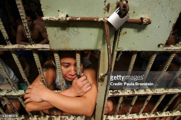 Prisoner looks out from a cell packed with several dozen inmates at the Navotas Municipal jail July 17, 2005 in Navotas, Manila, Philippines....