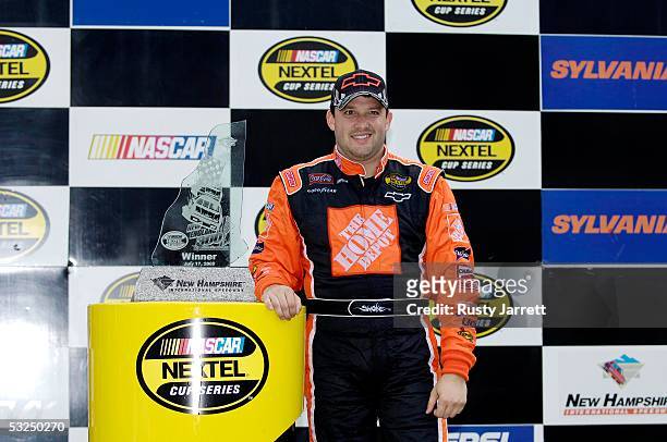 Tony Stewart, driver of the Chevrole, poses for photos with the trophy after winning the NASCAR Nextel Cup Series New England 300 on July 17, 2005 at...