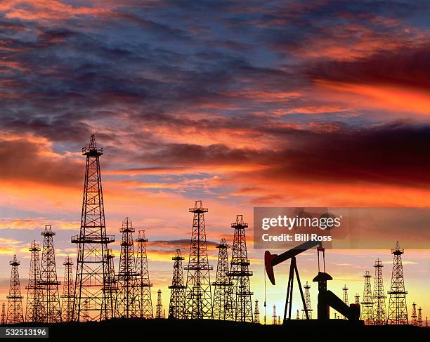 silhouette of oil field at sunset - industria petrolifera foto e immagini stock