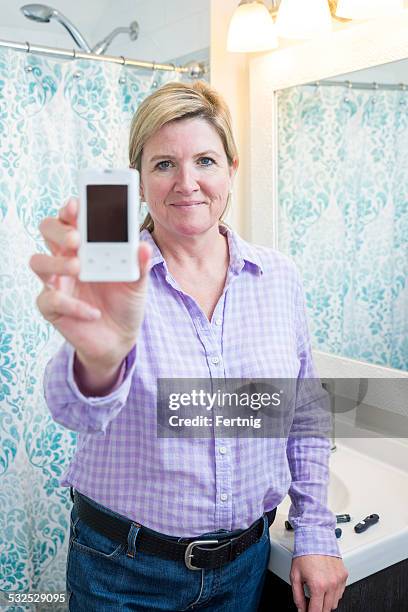 diabetic person holding-up a glaucometer. - glaucometer stock pictures, royalty-free photos & images