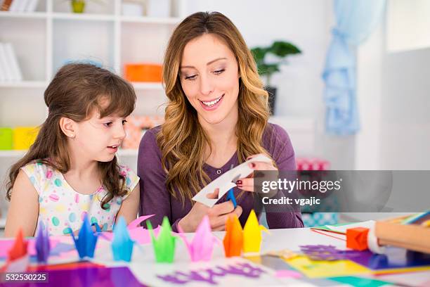 mother and daughter making origami. - origami instructions stock pictures, royalty-free photos & images