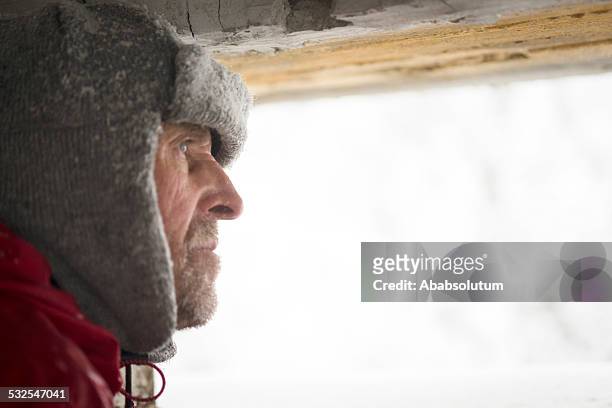 senior man looking  through great war's bunker porthole , snowing, europe - gulag stock pictures, royalty-free photos & images