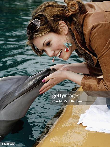 Singer Delta Goodrem plays with dolphins at Sea World on July 19, 2005 in Main Beach, Gold Coast, Australia.