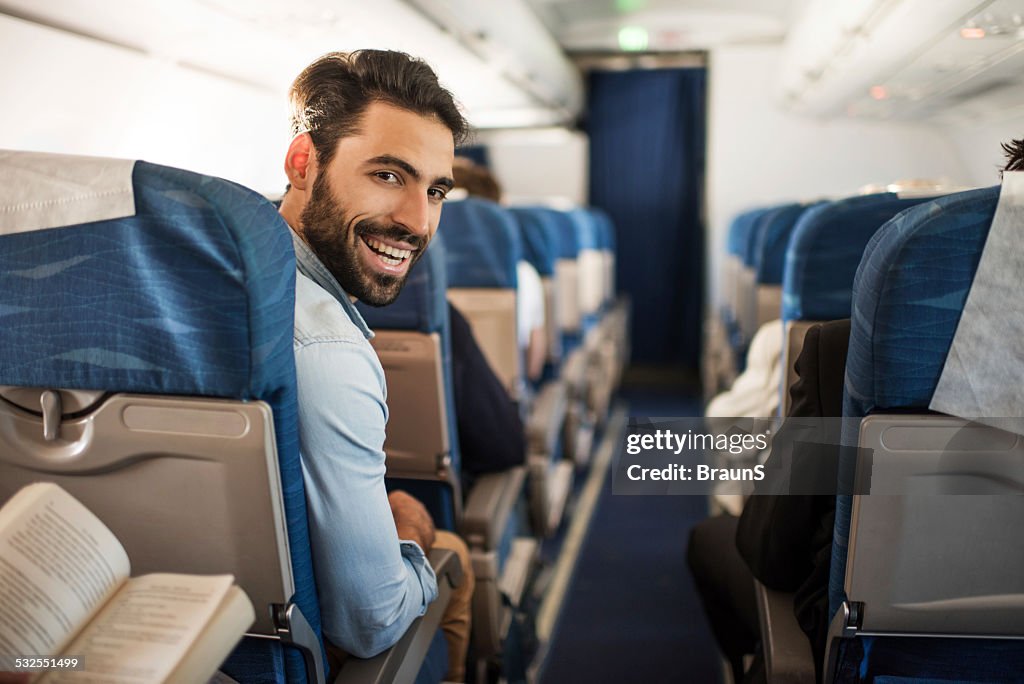 Smiling young man traveling by plane.