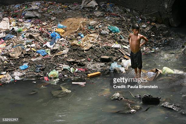 Filipino boy stands in a polluted canal in the slums on July 19, 2005 in Manila, Philippines. Extreme poverty is commonplace in Manila where...