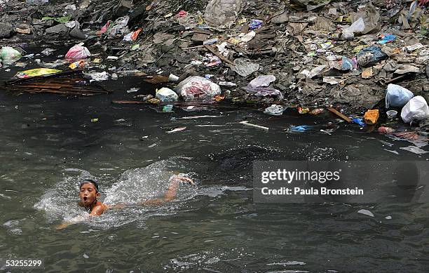 Filipino boy swims in a polluted canal in the slums on July 19, 2005 in Manila, Philippines. Extreme poverty is commonplace in Manila where...