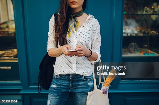 giovane donna che usa il smartphone parigina - boulangerie paris foto e immagini stock