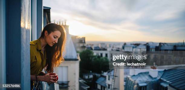 young woman relaxing on the balcony of her parisian apartment - paris balcony stock pictures, royalty-free photos & images