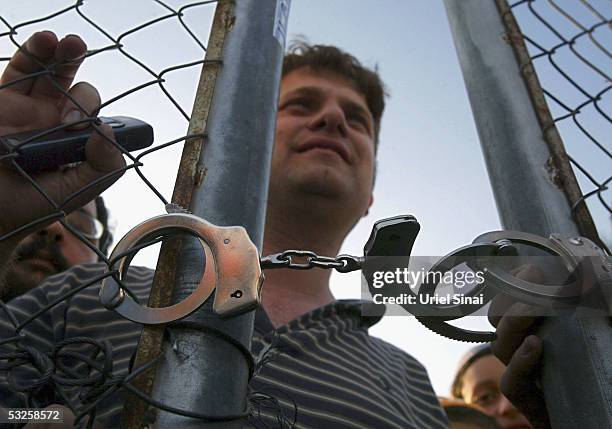 Right-wing Israeli activists looks through a gate locked with handcuffs by police enforcing a blockade round the farming community of Kfar Maimon...