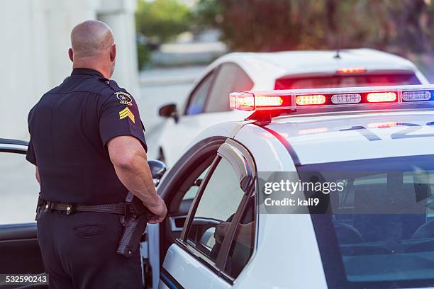 police officer getting out of cruiser - politiedienst stockfoto's en -beelden