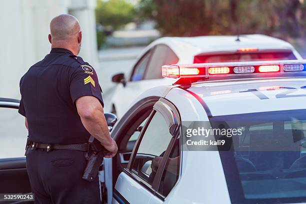 police officer getting out of cruiser - police stock pictures, royalty-free photos & images