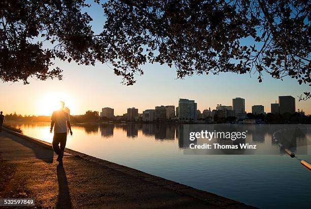 man walking at sunset along lake - oakland california bildbanksfoton och bilder