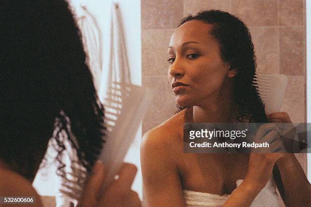 woman in bathroom combing hair - gekruld haar stockfoto's en -beelden