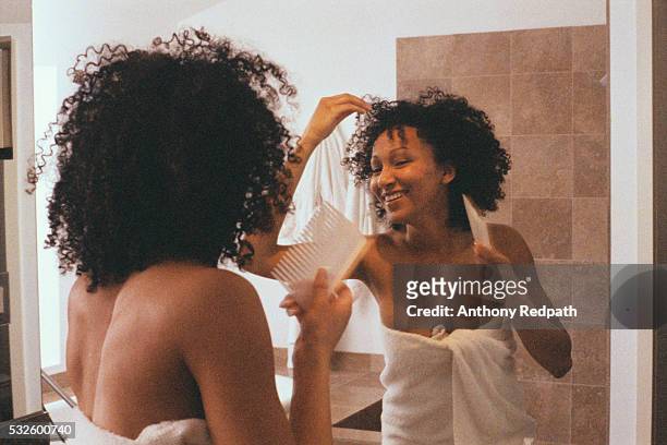 woman in bathroom combing hair - african american women wet stock-fotos und bilder