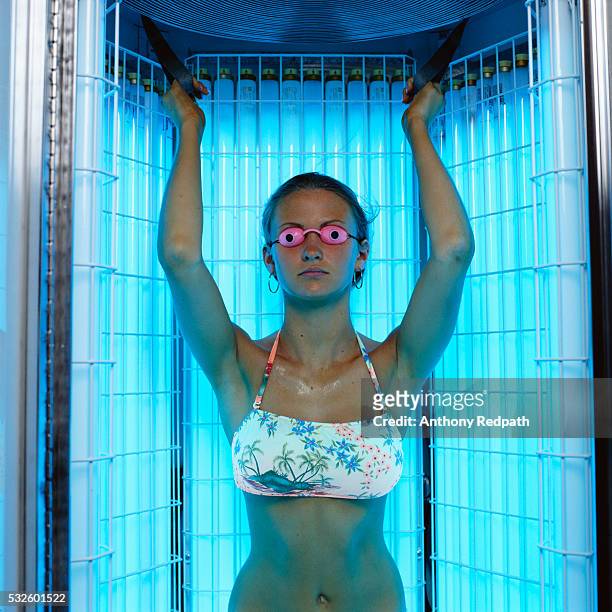woman standing in tanning booth - gebruind stockfoto's en -beelden