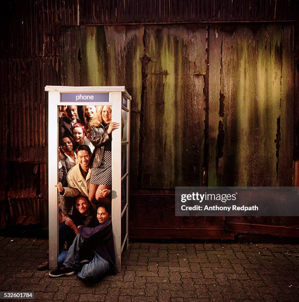 people crowded into a phone booth - telefonzelle stock-fotos und bilder