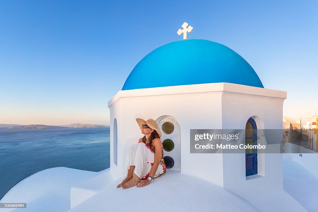 Woman on blue domed church in Santorini, Greece