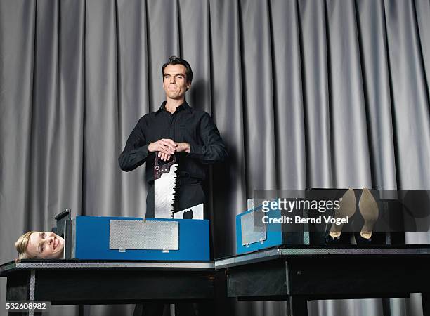 magician with saw and his assistant during performance - magician stock pictures, royalty-free photos & images