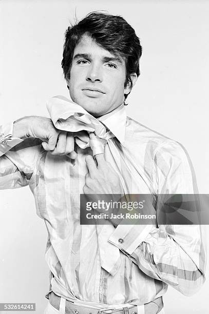 Portrait series of actor Warren Beatty as he knots his necktie, late 1960s or early 1970s.