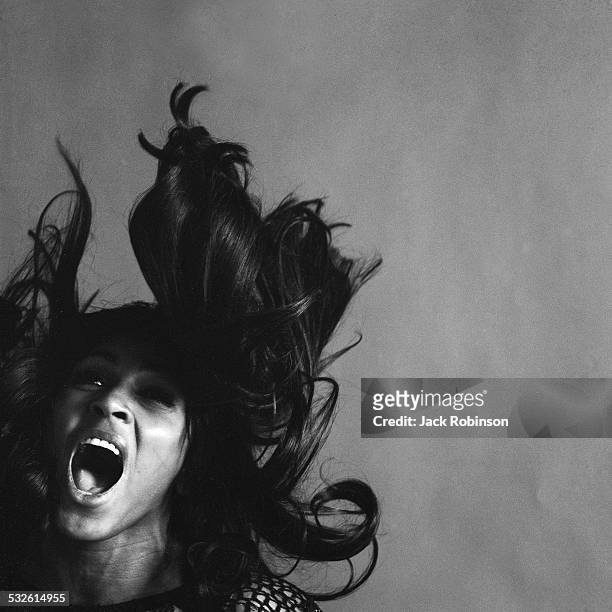Studio portrait of American rock singer Tina Turner, wearing a dark crocheted mini-dress, singing while her long dark hair flies around her face, New...