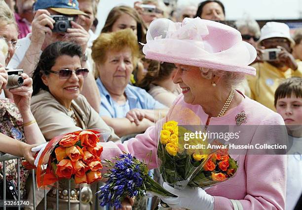 Queen Elizabeth II receives flowers during a walkabout on the promenade on July 20, 2005 in Dover, England. The Queen officially opened two passenger...