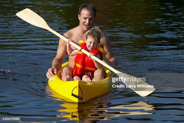 father and son kayaking on a lake - family red canoe stock pictures, royalty-free photos & images