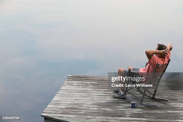 man sitting on dock at lake - coffee cup top view stockfoto's en -beelden