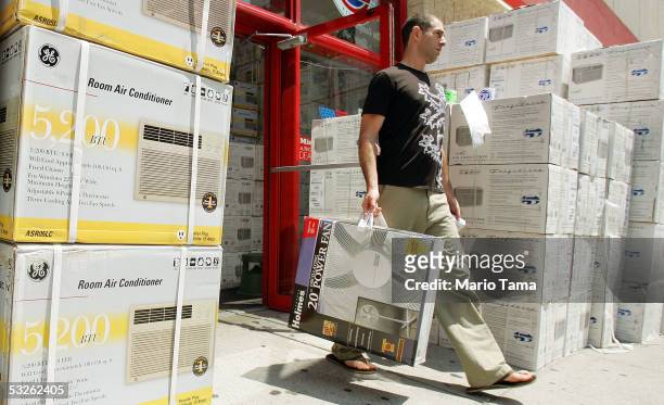 Man carries a new fan out of a PC Richard store next to boxes of air conditioners for sale July 20, 2005 in New York City. Temperatures are expected...