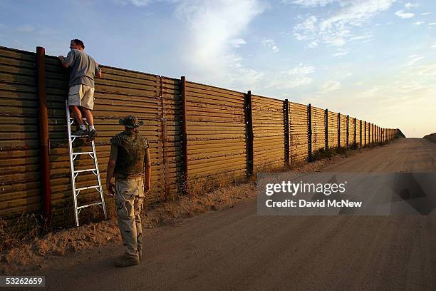 Volunteers look over the US-Mexico border fence to see how illegal border crossers may jump the fence before going on the nightly patrol by citizen...