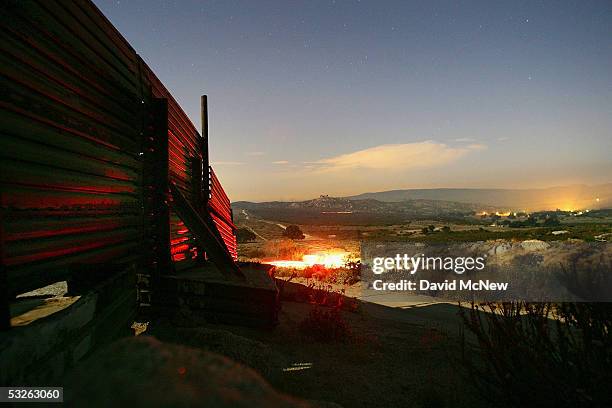 Red taillights of a passing vehicle shine on the US-Mexico border fence in the moonlight as nightly patrols by citizen volunteers searching for...