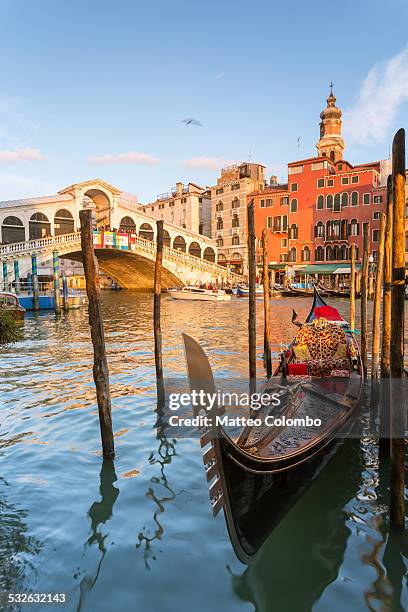 gondola moored at sunset at rialto bridge, venice - gondola traditional boat stockfoto's en -beelden