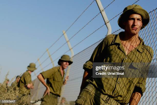 Israeli soldiers stand stand watch July 20, 2005 at a fence surrounding the Israeli town of Kfar Maymon. Thousands opposing the Israeli pullout from...