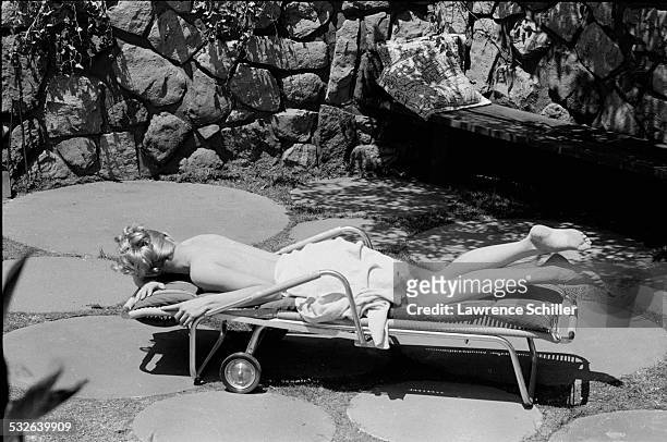 American actress Julie Newmar, covered only in a towel, sunbathes in a scene from the film 'The Marriage-Go-Round' , Los Angeles, California, 1960 .