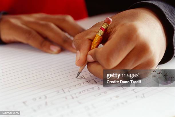 schoolboy writing with chewed-up pencil stub - spelling stock photos et images de collection