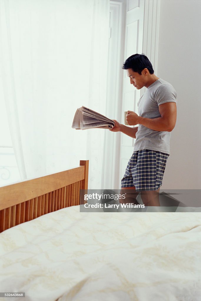 Man Reading Newspaper in Bedroom