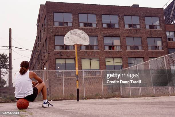 woman sitting alone on basketball court - vintage basketball court stock pictures, royalty-free photos & images