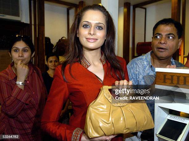 Miss India-Universe 2005, Amrita Thapar is surrounded by inquisitive bystanders as she poses with a bag from the new 'Riviera' collection from...