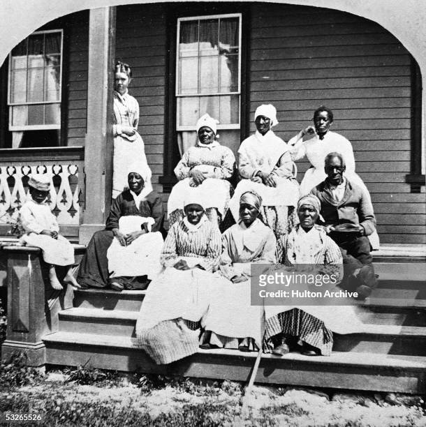 Group of women and a man, presumably enslaved, sit on the steps of the Florida Club, St. Augustine, Florida, mid 19th Century. A white woman,...
