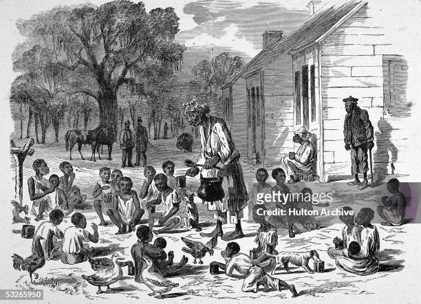 Grossly caricaturistic illustration shows an enslaved woman as she serves food to enslaved children behind the shacks in which they must live on a...