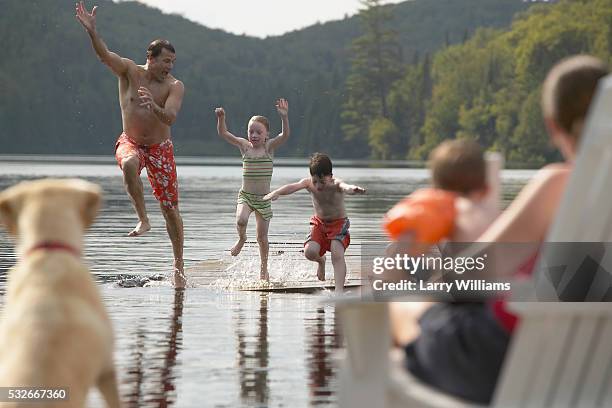 father jumping into lake with children - dog swimming stock pictures, royalty-free photos & images