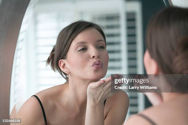 woman blowing herself a kiss in the mirror - eitelkeit stock-fotos und bilder