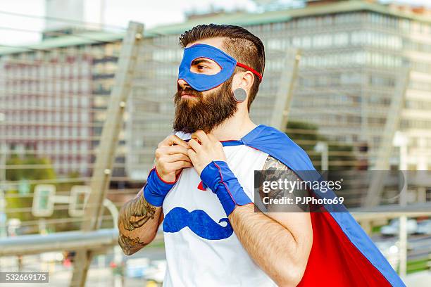 hipster superhero adjusting his mantle - cosplay stockfoto's en -beelden