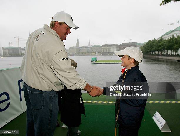 John Daly of USA shakes hands with Christoph Schierholz who had a hole in one at the beat the pro competition before the rain delayed first round of...