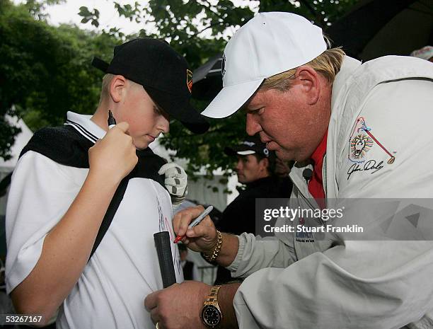 John Daly of USA signs the tee shirt of a young fan after the beat the pro competition before the rain delayed first round of The Deutsche Bank...